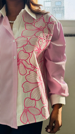 Person wearing a pink floral-patterned shirt with a white collar.